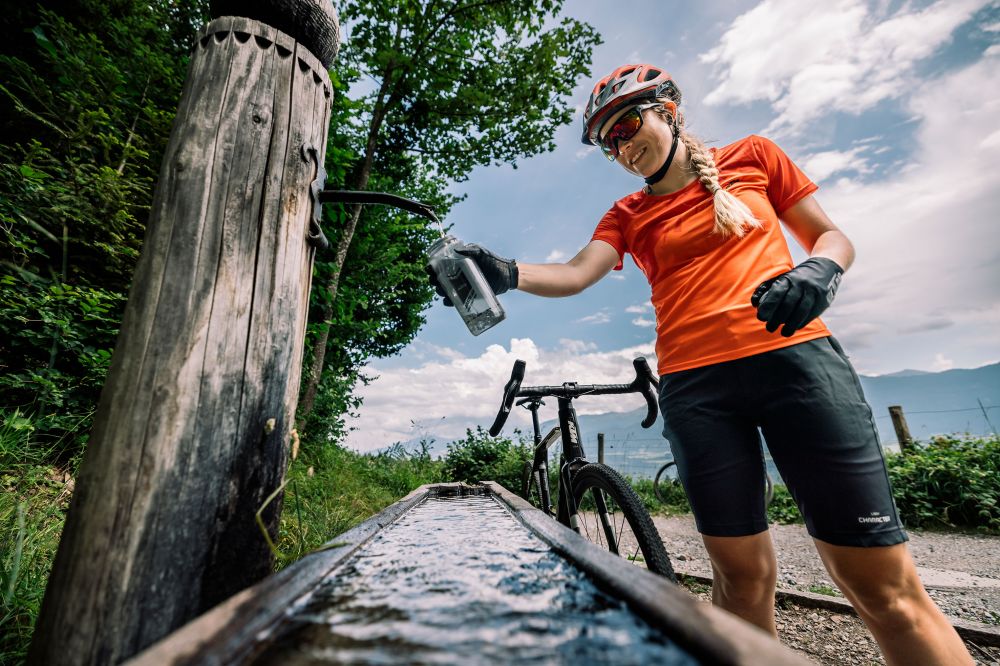Radfahrerin in orange trinkt Wasser