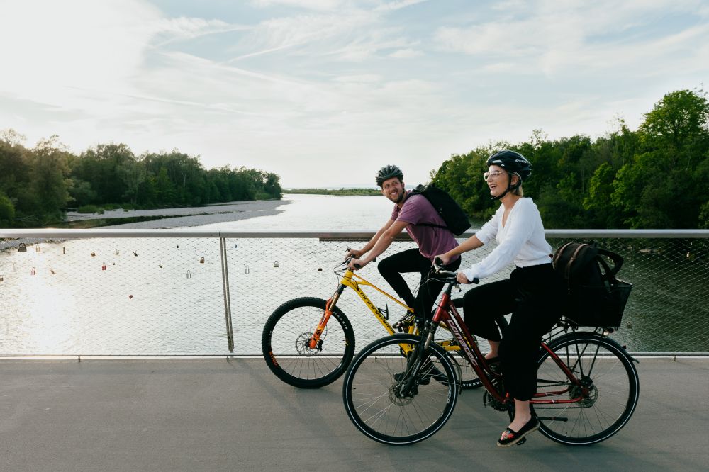 Mann und Frau fahren mit dem Fahrrad über eine Brücke.